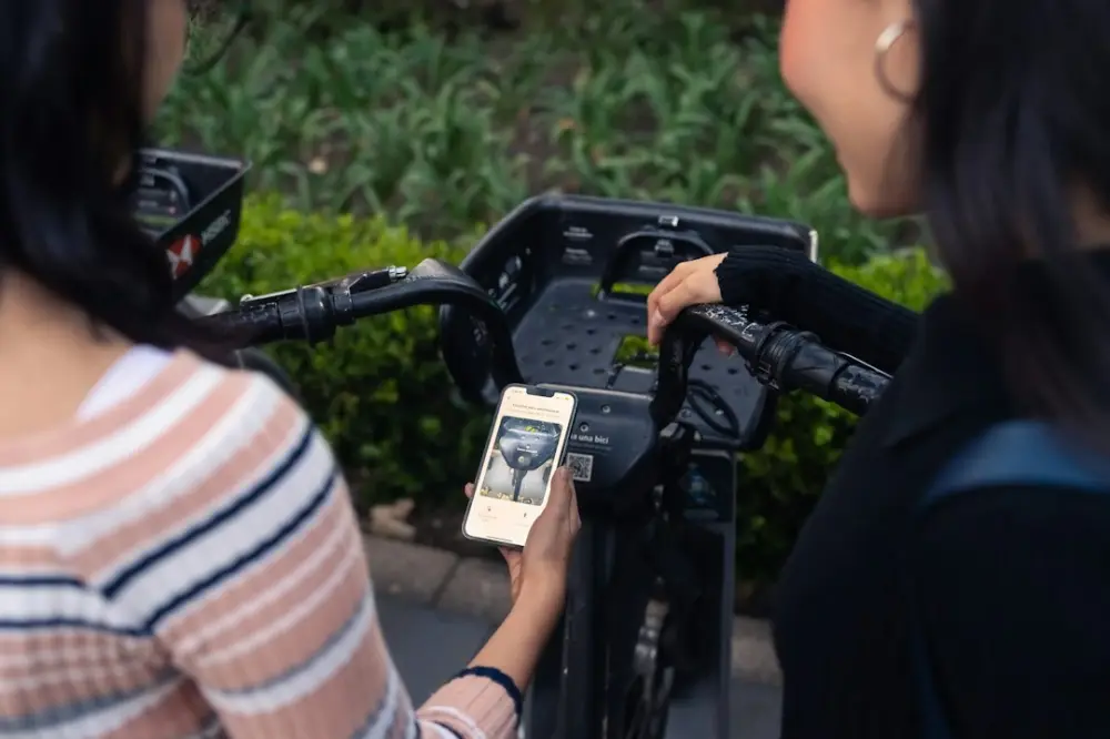 Two women using a smartphone with a bike's handlebars, illustrating smart city infrastructure